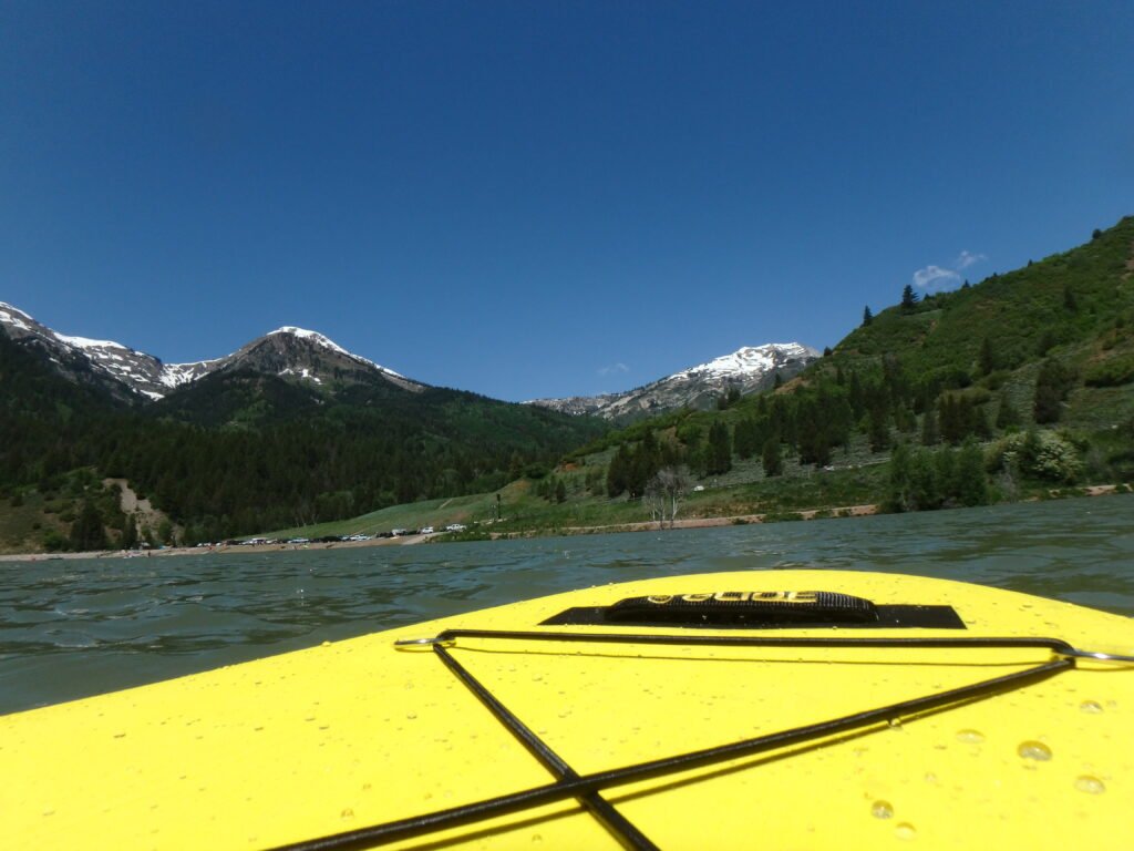 Glide O2 Retro All Around Paddle Board with a 5 star rating showing snow capped mountains in the background.